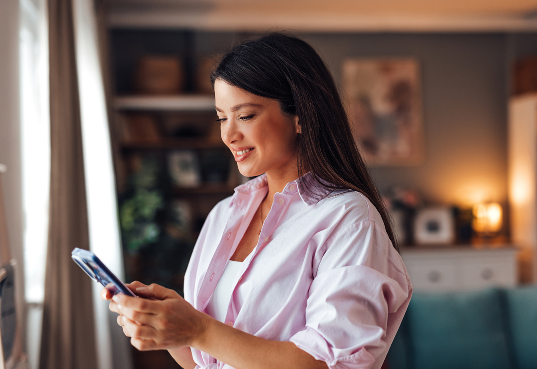 Femme professionnelle utilisant son smartphone à la maison pour gérer son assurance emprunteur