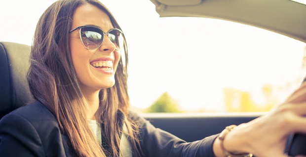 Femme souriante au volant d’une voiture d’occasion