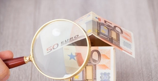  Une loupe sur une maison en billets euros