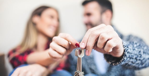  Un couple tenant des clefs de leur bien immobilier
