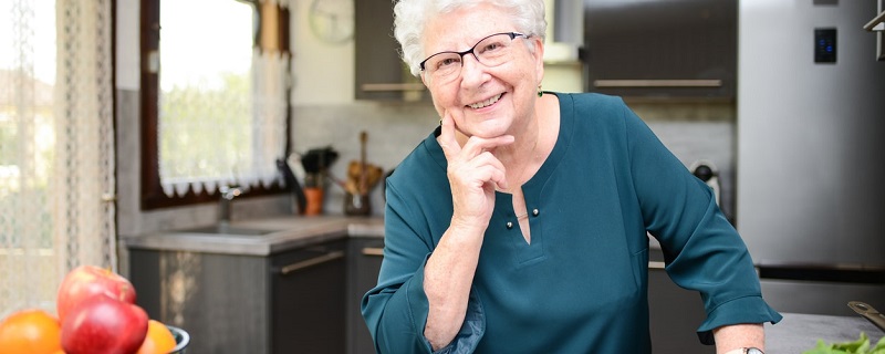 femme retraitee heureuse dans sa cuisine