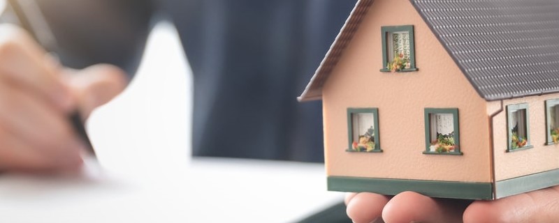 agent immobilier tient un modèle de maison