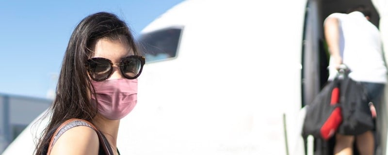 femme avec un masque devant un avion