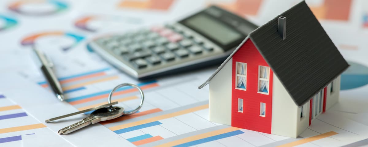 Maison miniature, clés et calculatrice sur des documents financiers