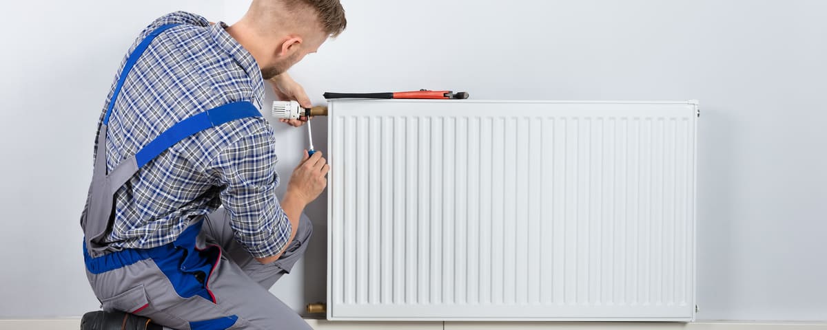 Plombier qui r&eacute;pare un radiateur