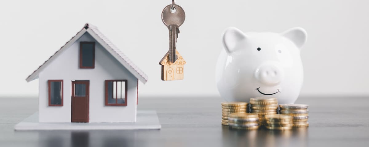 Un mod&egrave;le maison, une tirelire et des pi&egrave;ces de monnaie