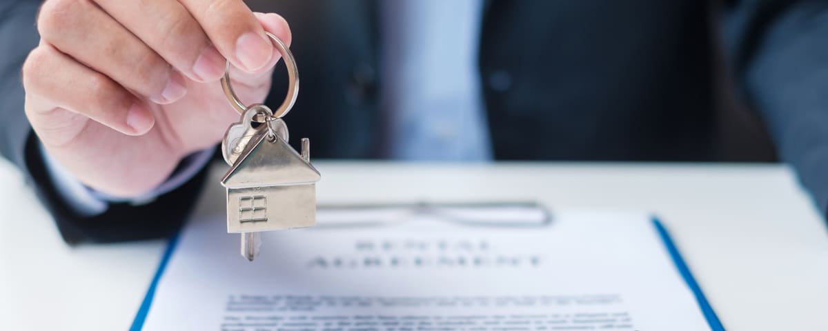 Homme tenant la clé de la maison lors de la signature des documents contractuels.
