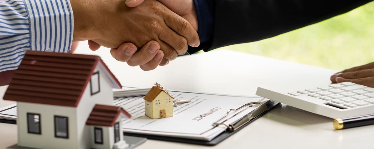 Une poignée de main entre le représentant des ventes et le propriétaire lors de la signature d’un contact d’achat de maison