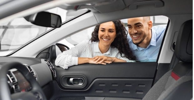 Jeune couple joyeux achetant une nouvelle voiture