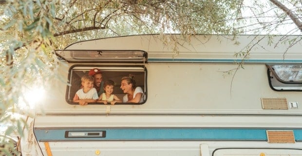 vue d'une famille, sourriant à la fenêtre d'une caravane